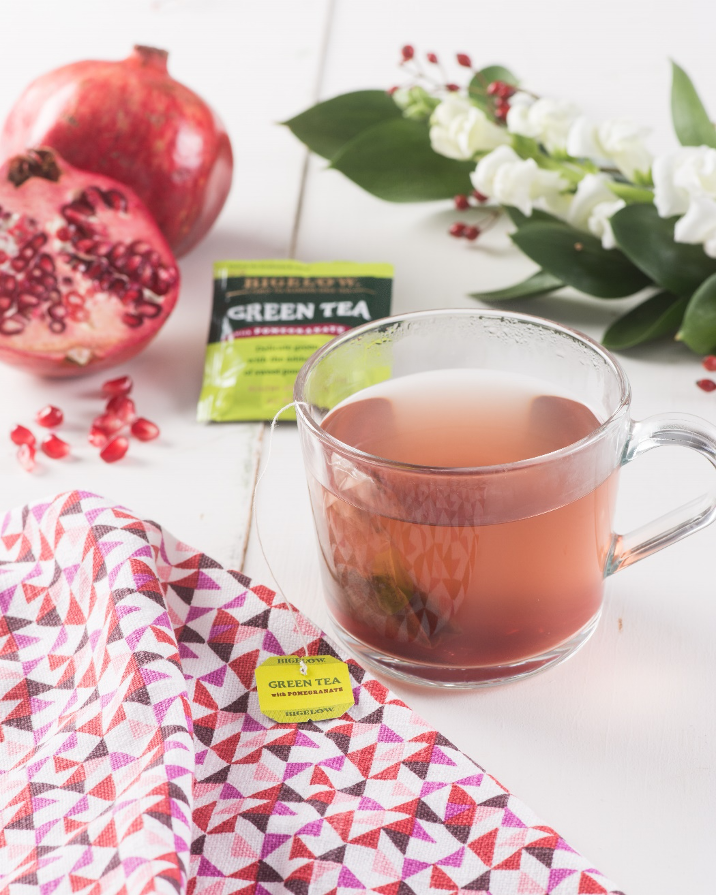 Bigelow Green Tea with Pomegranate tea bag, glass mug of tea on table with flowers